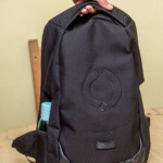 The larger padded handle across the top appears to provide some added strength and structure to the top of the bag, as well as providing a more comfortable grip when hand-carrying the backpack.